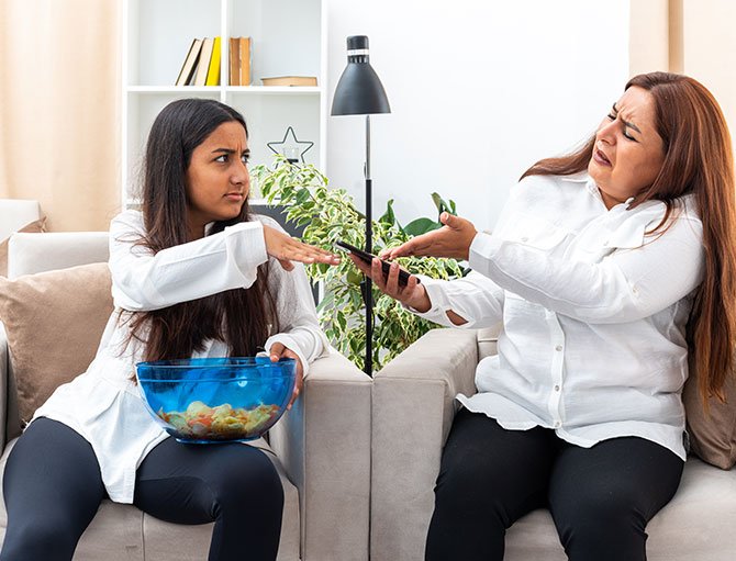 Two women on a couch exhibit frustration, symbolizing conflict in therapy at The Guidance House.