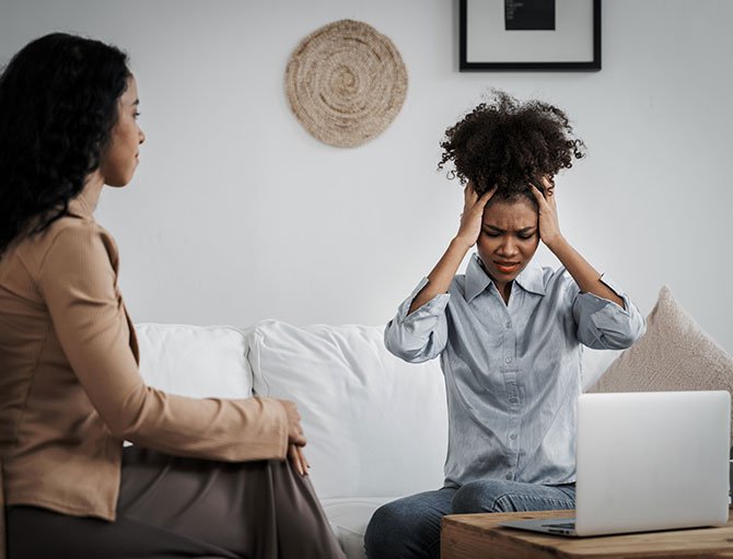 Two women discussing anxiety management in a calm living room, illustrating support and emotional distress.